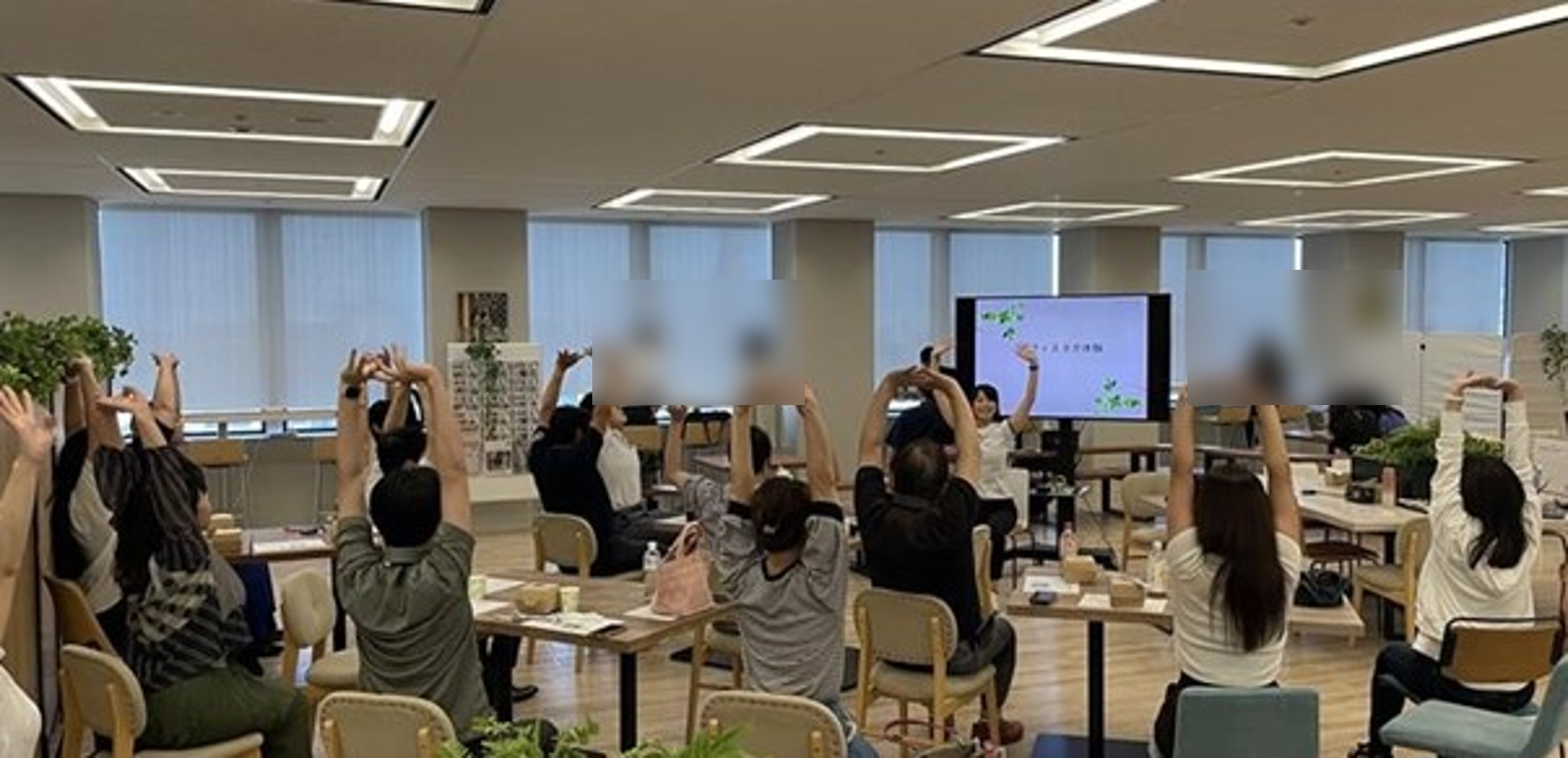 食堂でトレーナーと写真が両手を上にあげて伸びをしている画像