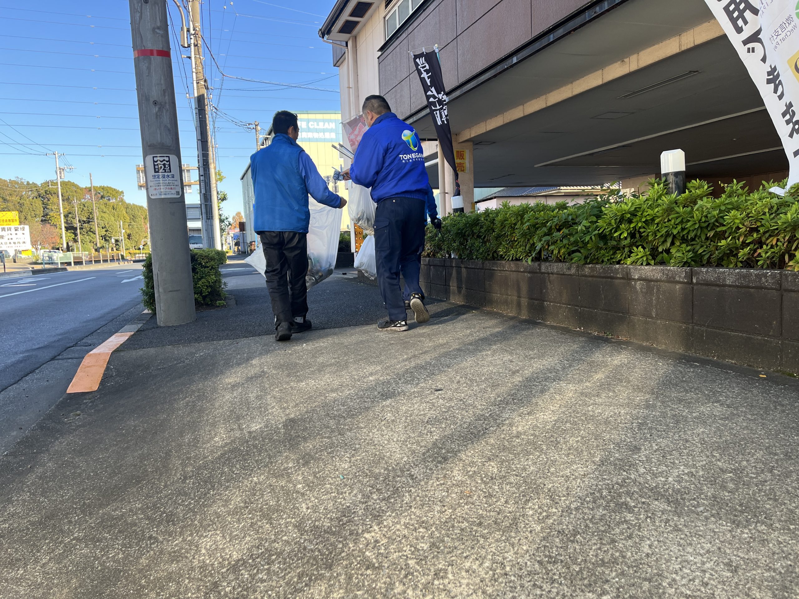 2人の社員がゴミ袋を店あっている写真