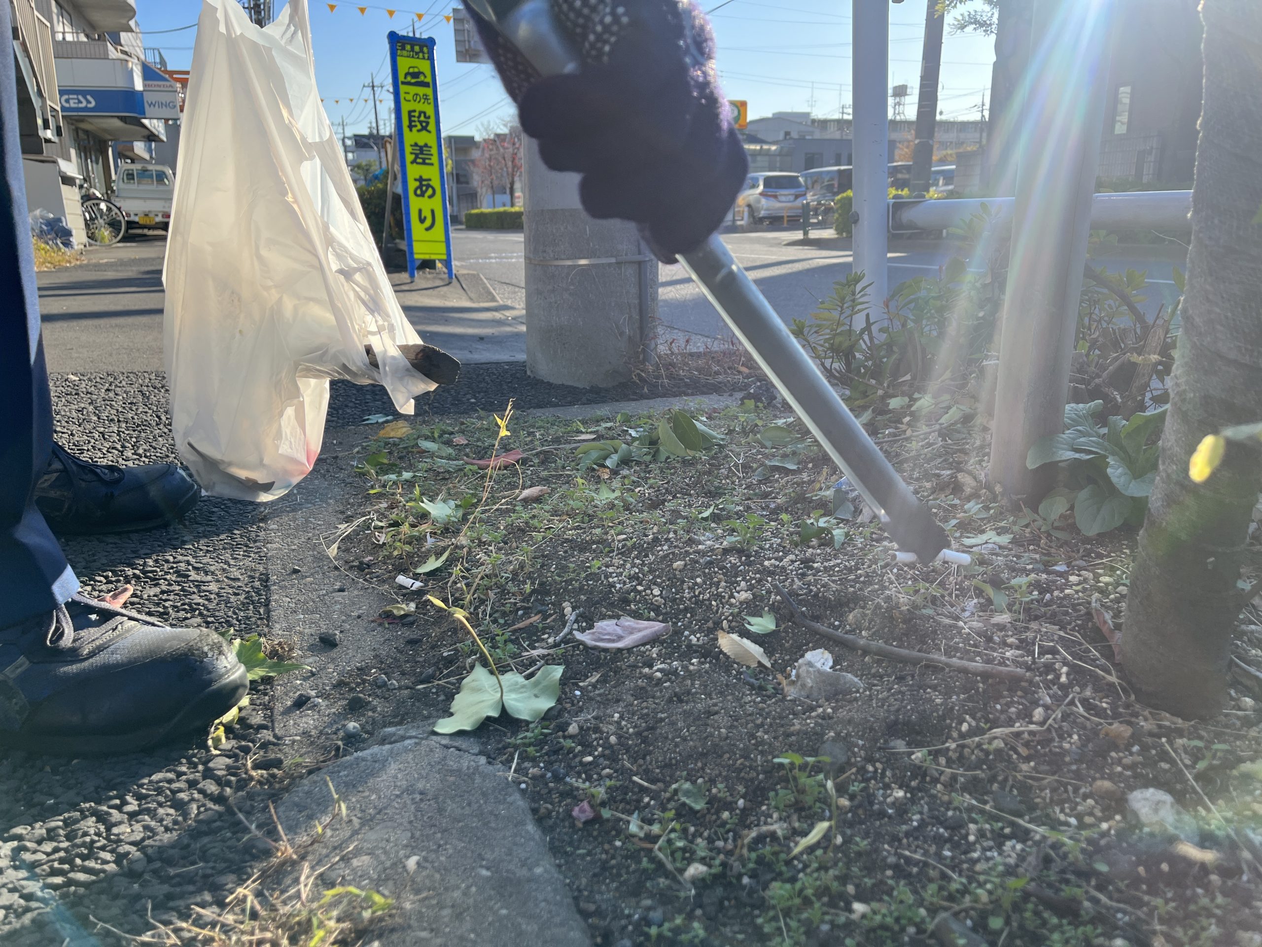 道路脇のゴミをトングで拾おうとしている写真