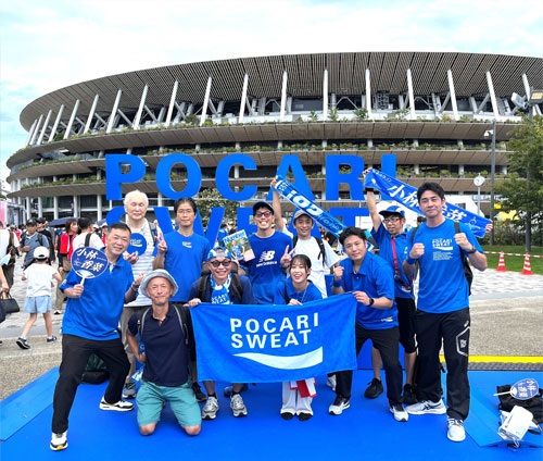 国立競技場を背景に社員が記念写真を撮った写真