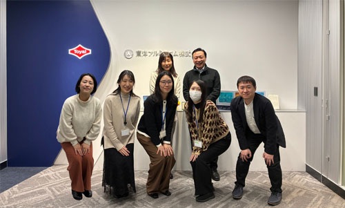 社員がオフィス看板の前で記念撮影をしている画像